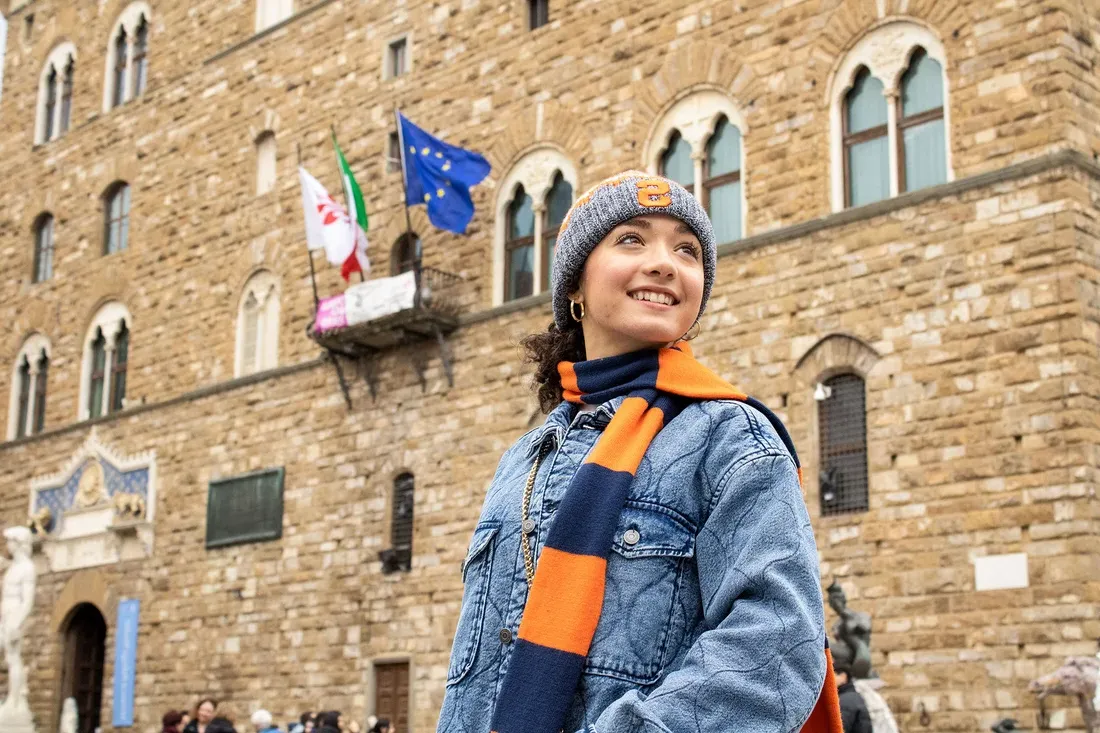 一名学生戴着雪城大学的围巾站在佛罗伦萨的一座建筑外.